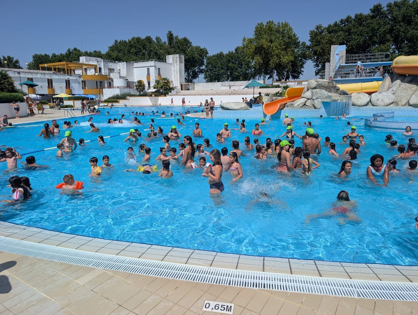 Crianças a divertirem-se no parque aquático, com escorrega e piscina
