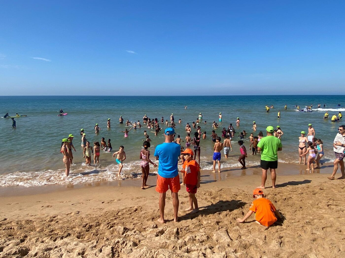 Grupo de crianças na praia num dia de céu limpo