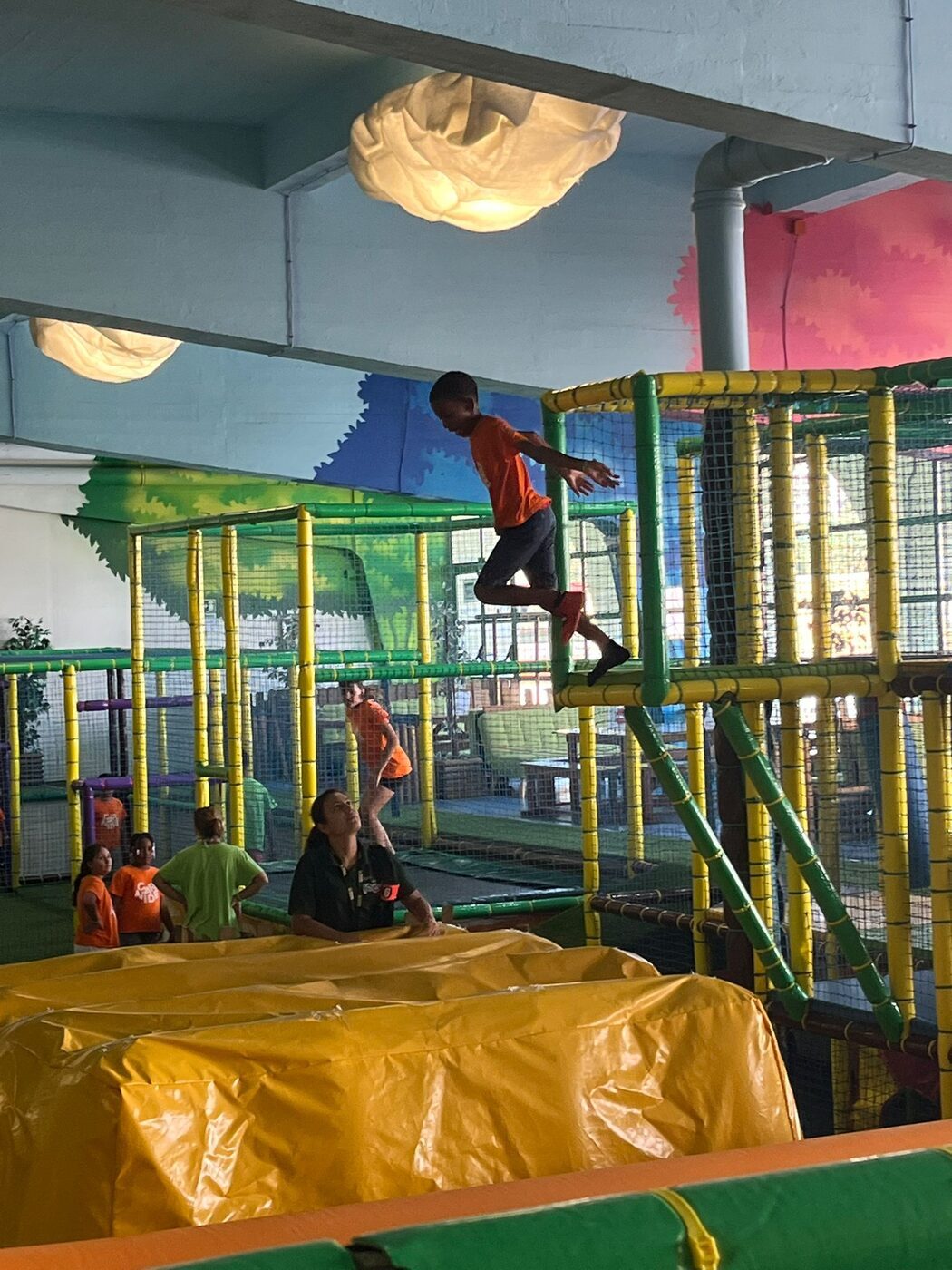 Criança a saltar numa estrutura de trepar do parque coberto