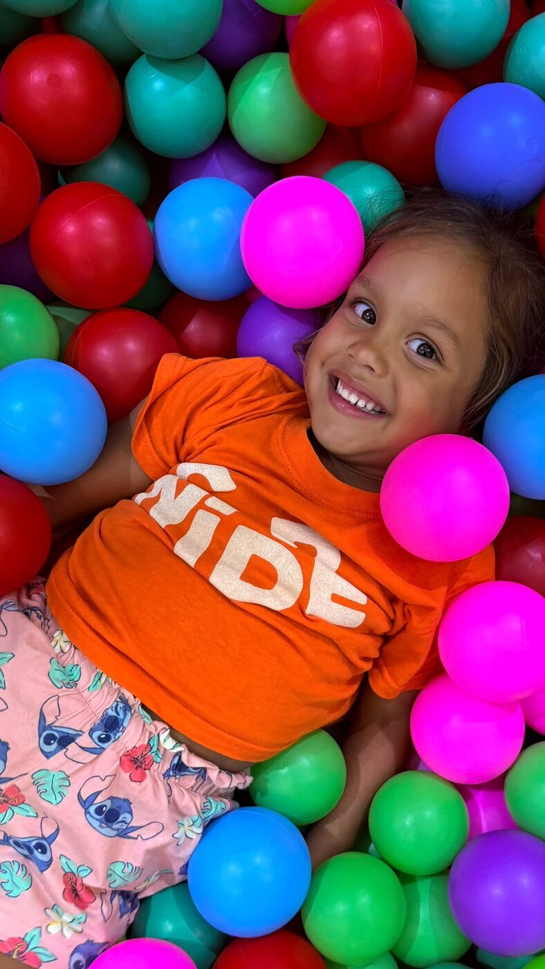 Menina sorridente na piscina de bolas