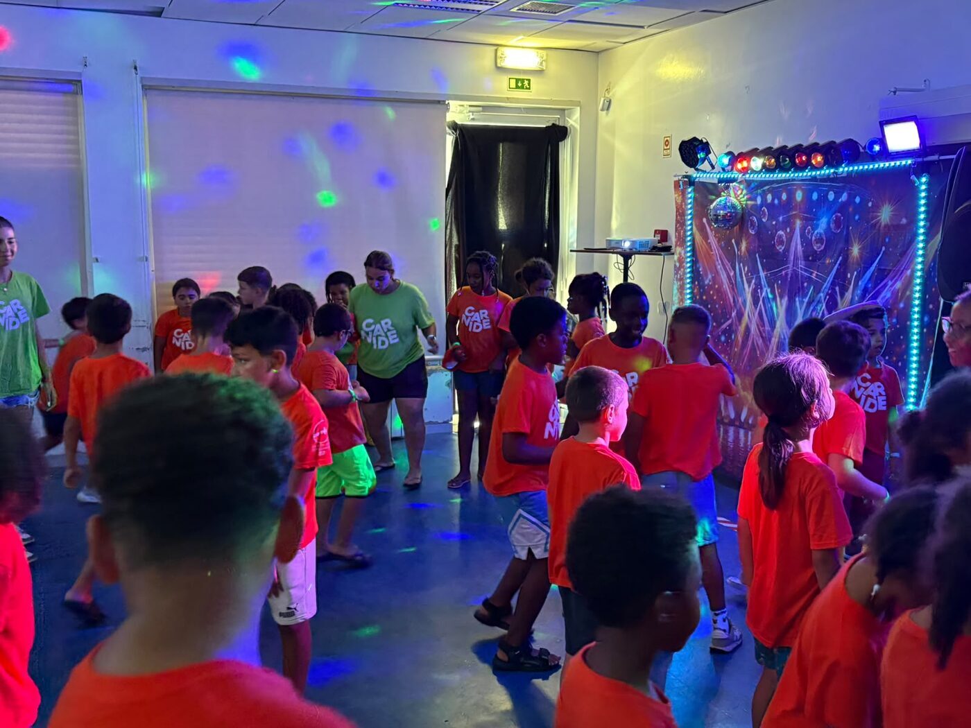 Crianças a dançar numa sala com luzes de discoteca