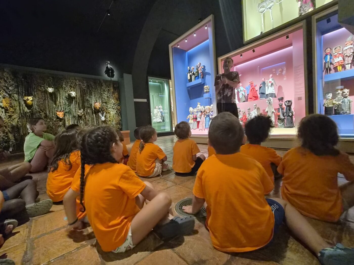 Crianças sentadas a ver uma parede de ecrãs numa exposição interactiva