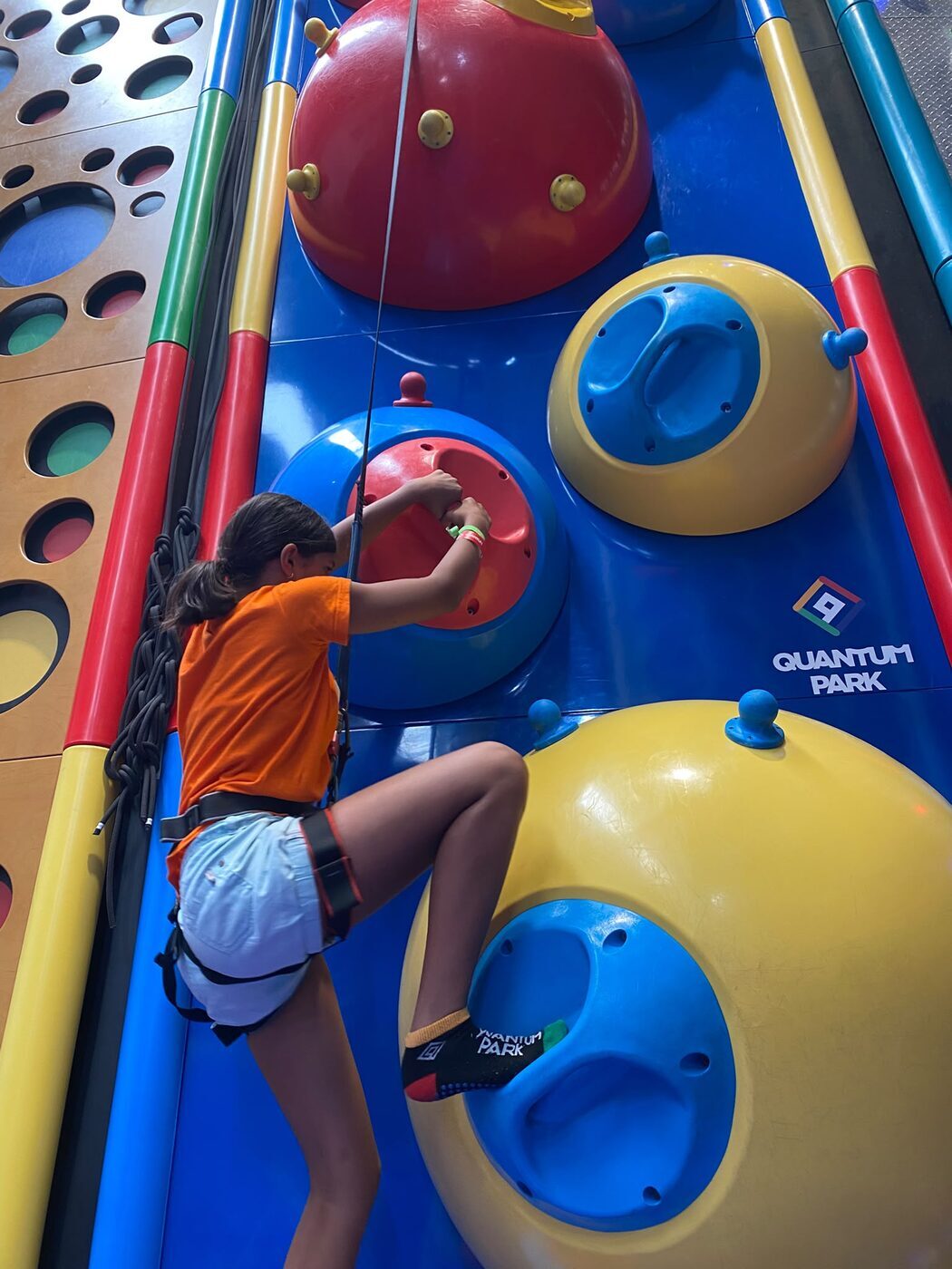 Criança a trepar uma estrutura de bolas gigantes num parque coberto