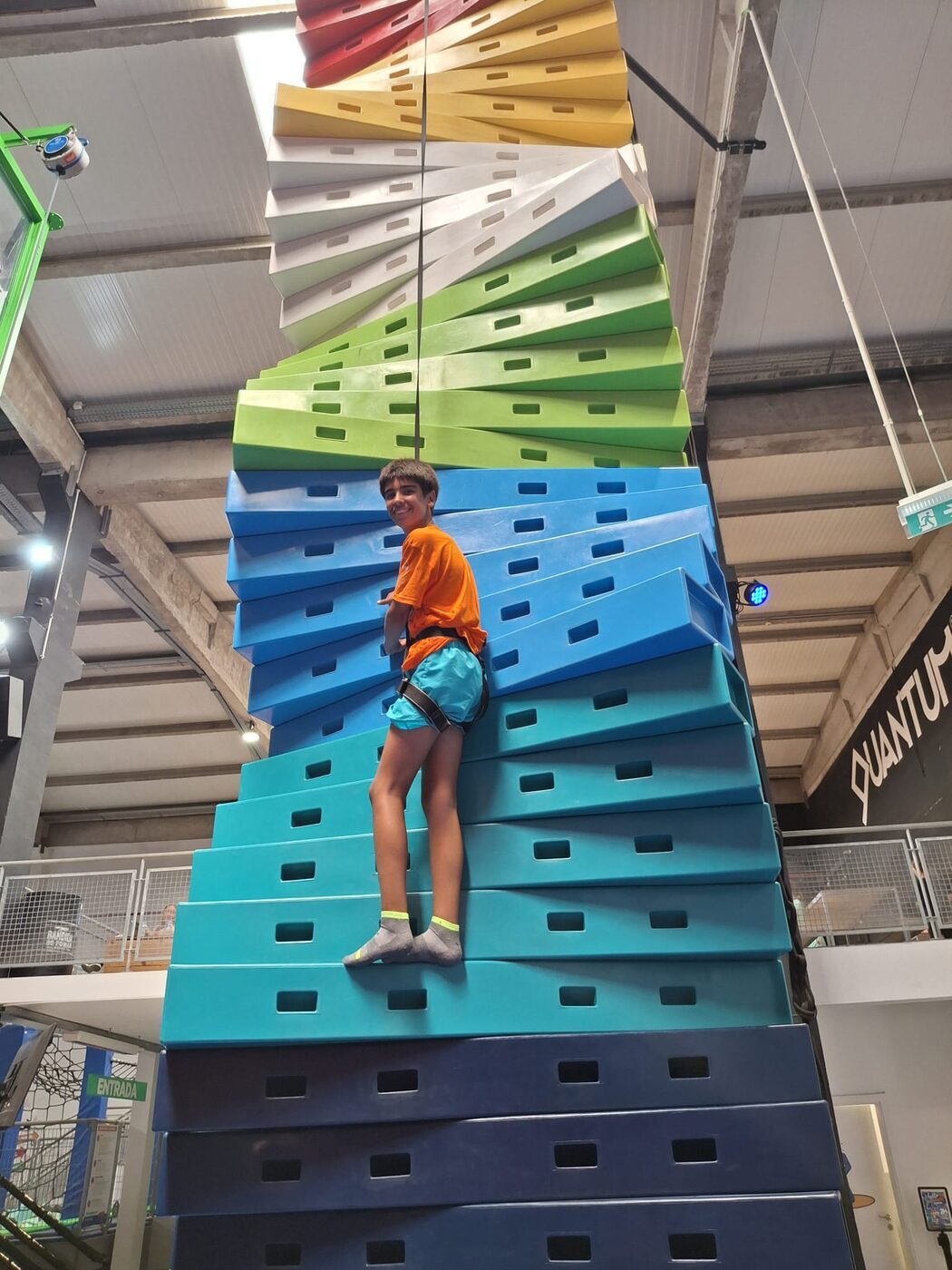 Criança a subir uma parede de escalada colorida