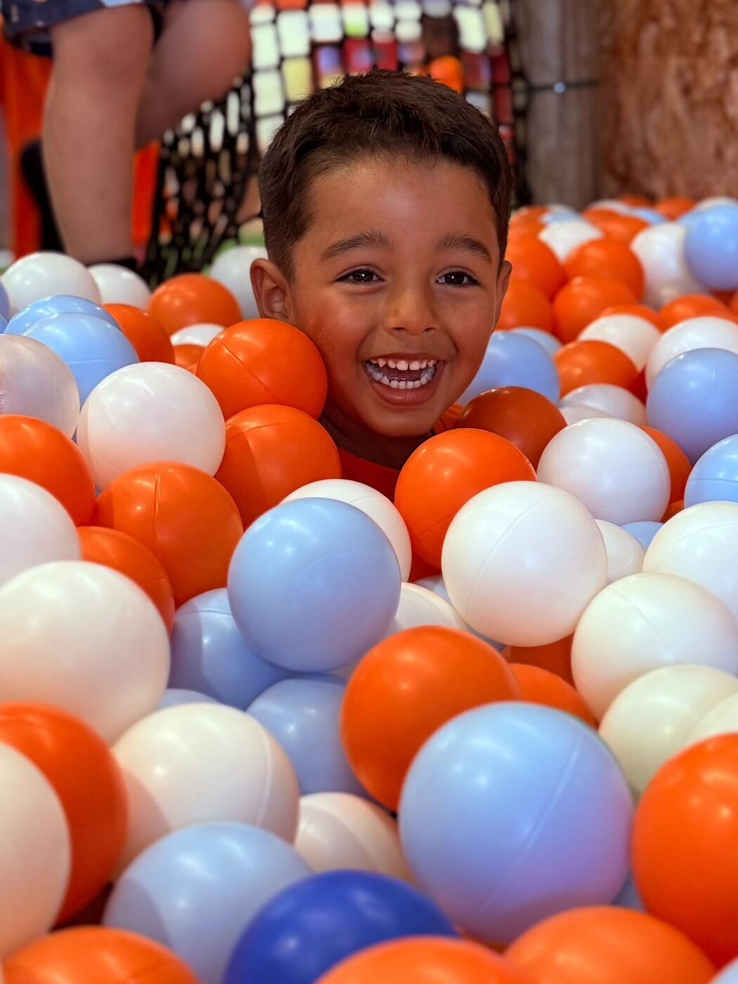 Menino sorridente numa piscina de bolas coloridas