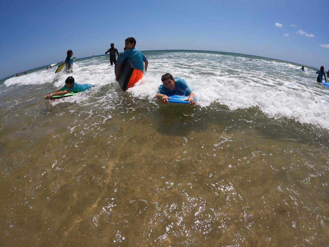 Monitor a ajudar crianças a apanhar ondas de bodyboard no mar