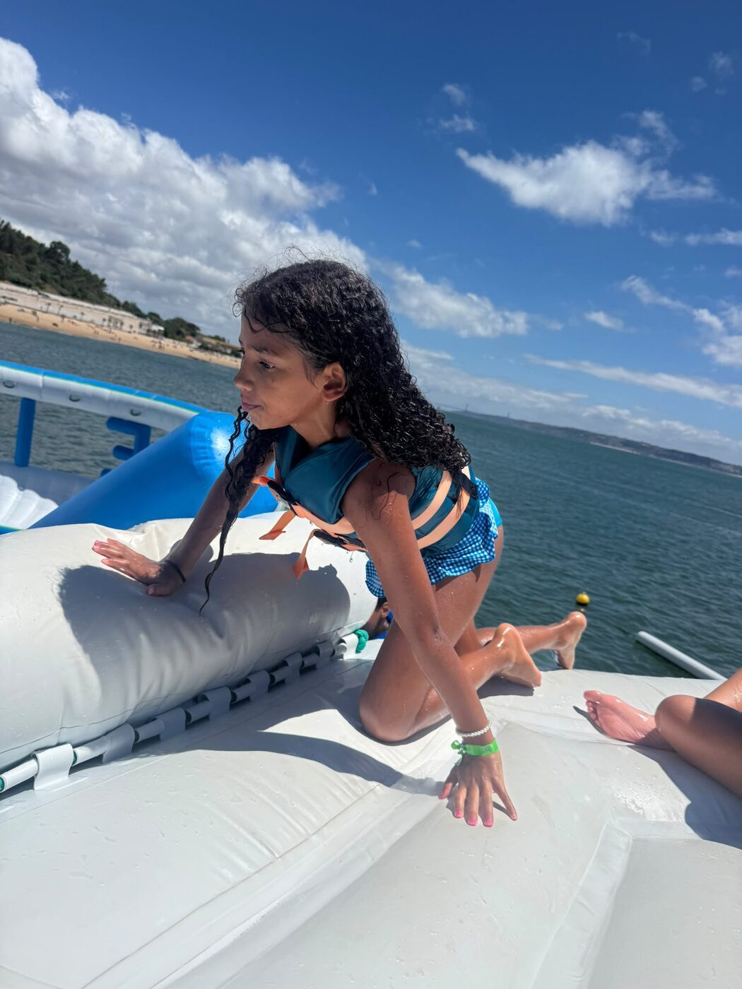 Menina a atravessar de gatas uma plataforma insuflável no mar