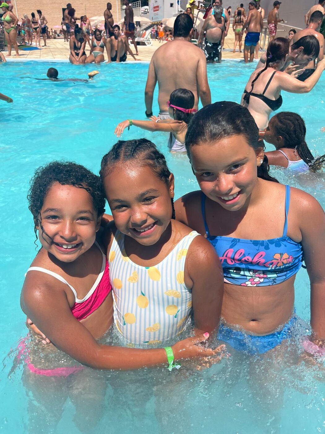 Três meninas abraçadas na piscina de ondas