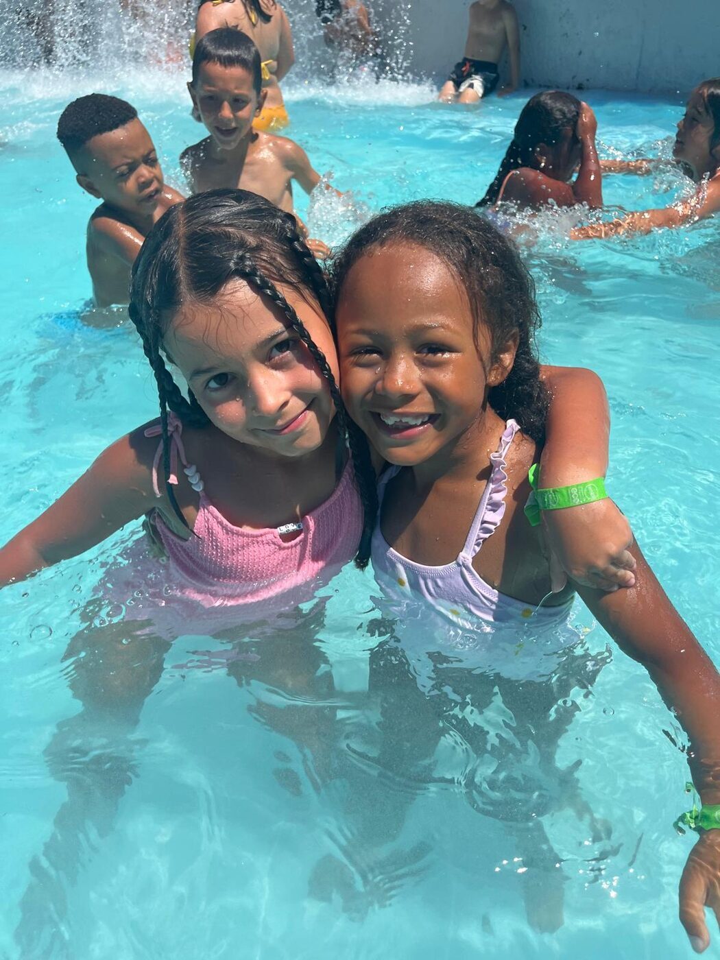 Duas meninas abraçadas dentro da piscina