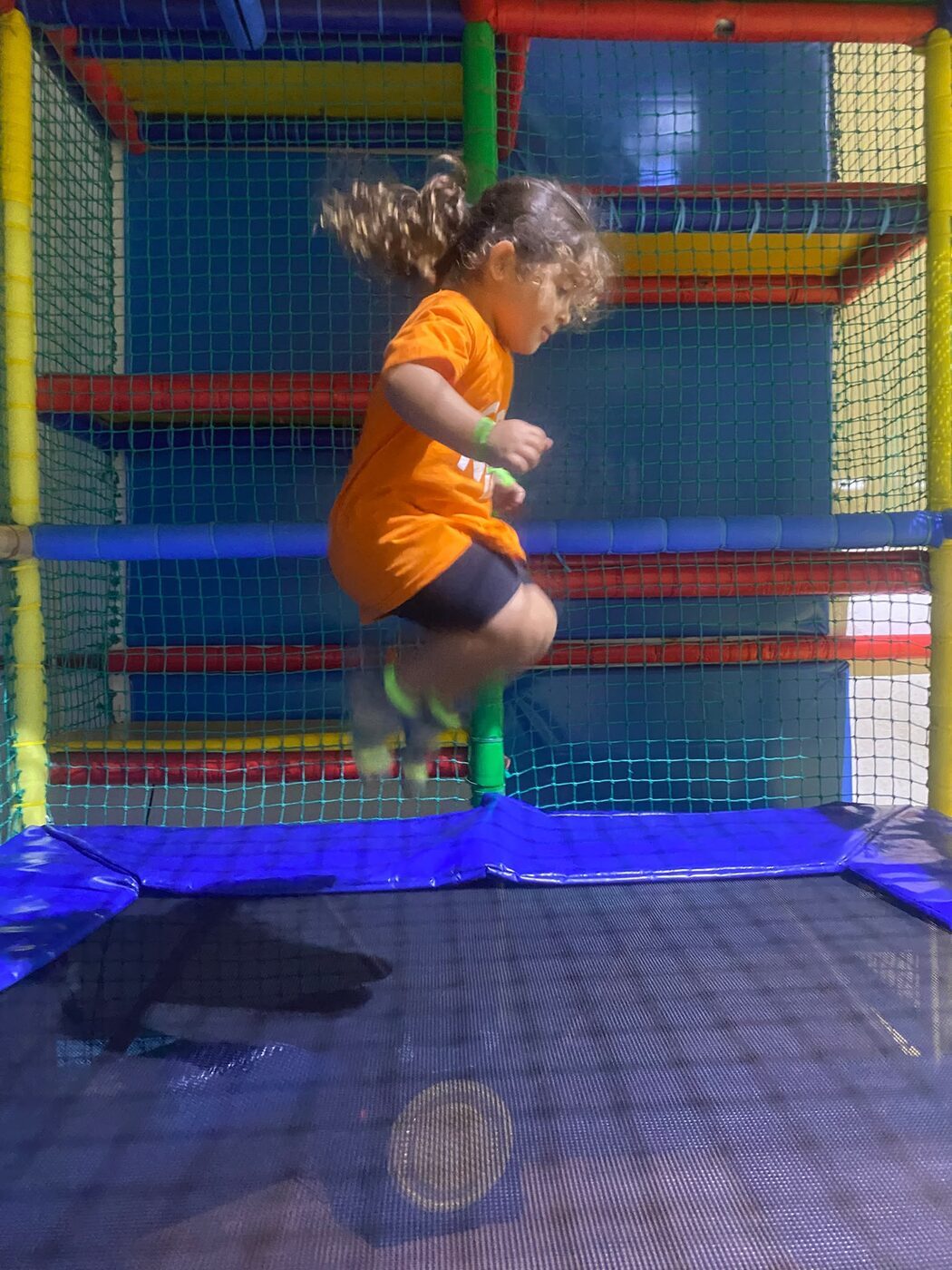 Menina a saltar num trampolim de um parque coberto